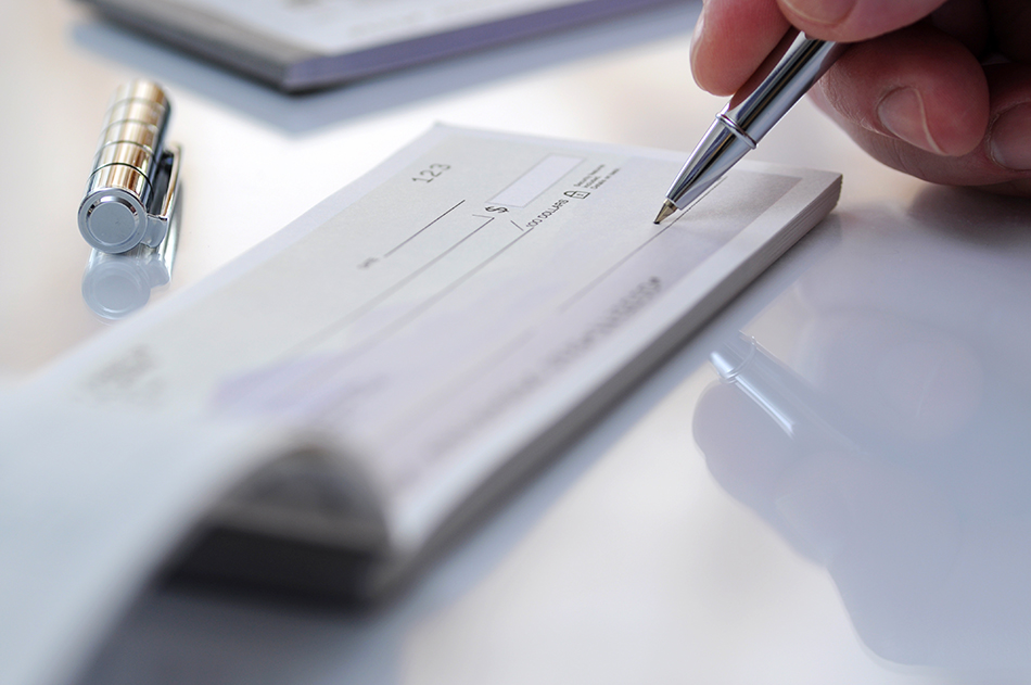 Person holding a pen and writing a donation check.